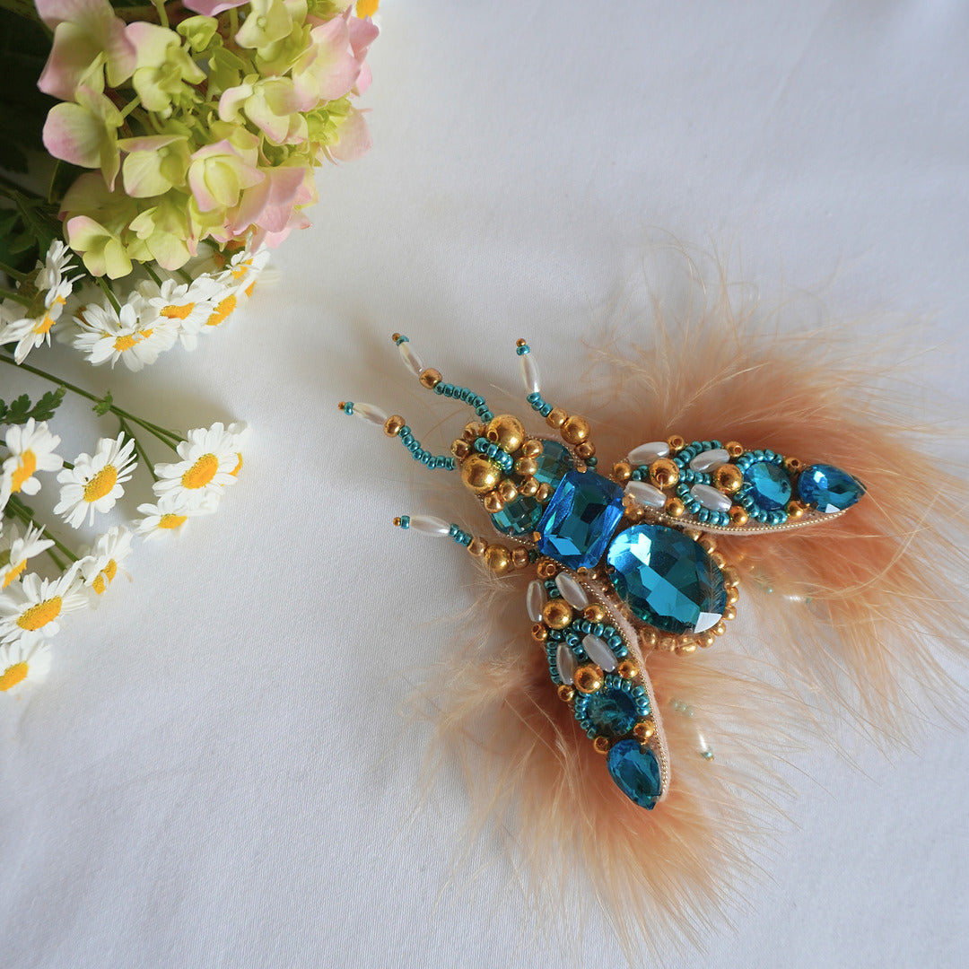 Decorative insect brooch with blue gemstones and peach feathers - TGbrooch