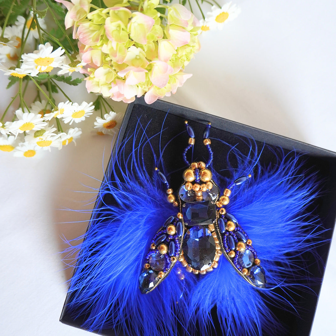 Embroidered TGbrooch with electric blue and gold beads and blue feathers