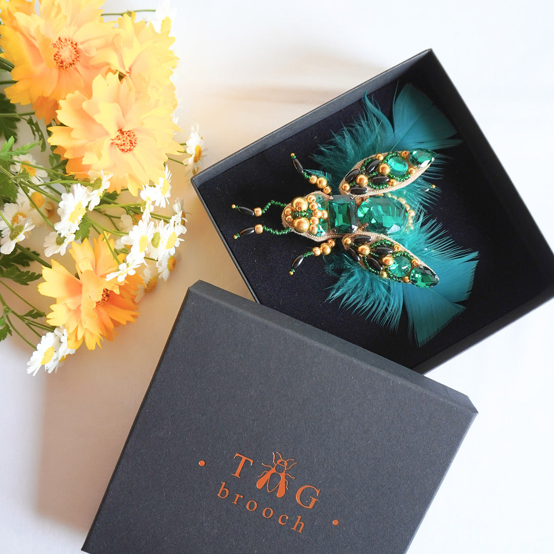 Handmade beaded TGbrooch with emerald green feathers and gold beads in TGbrooch box