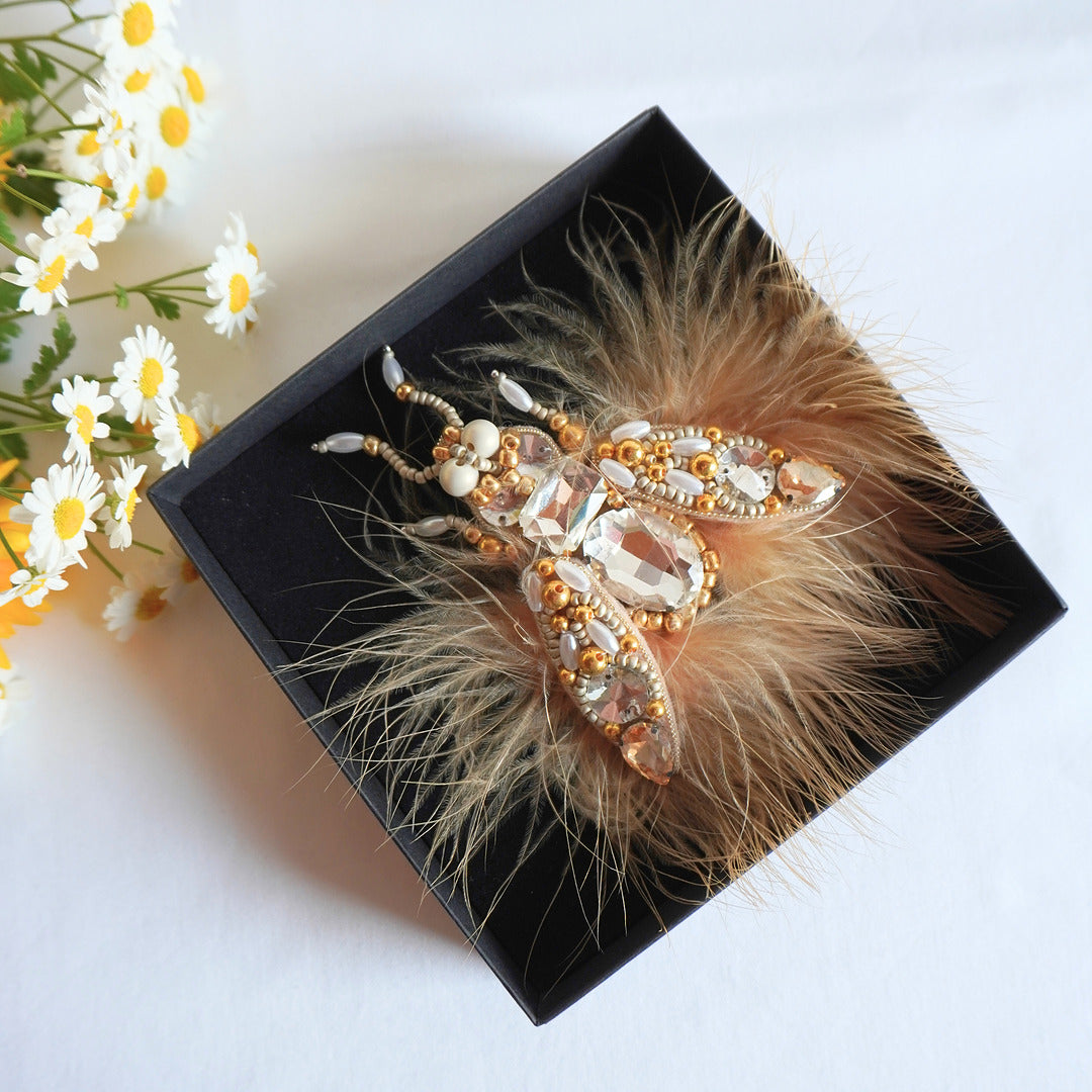 Decorative TGbrooch with feathers and beads on a black box