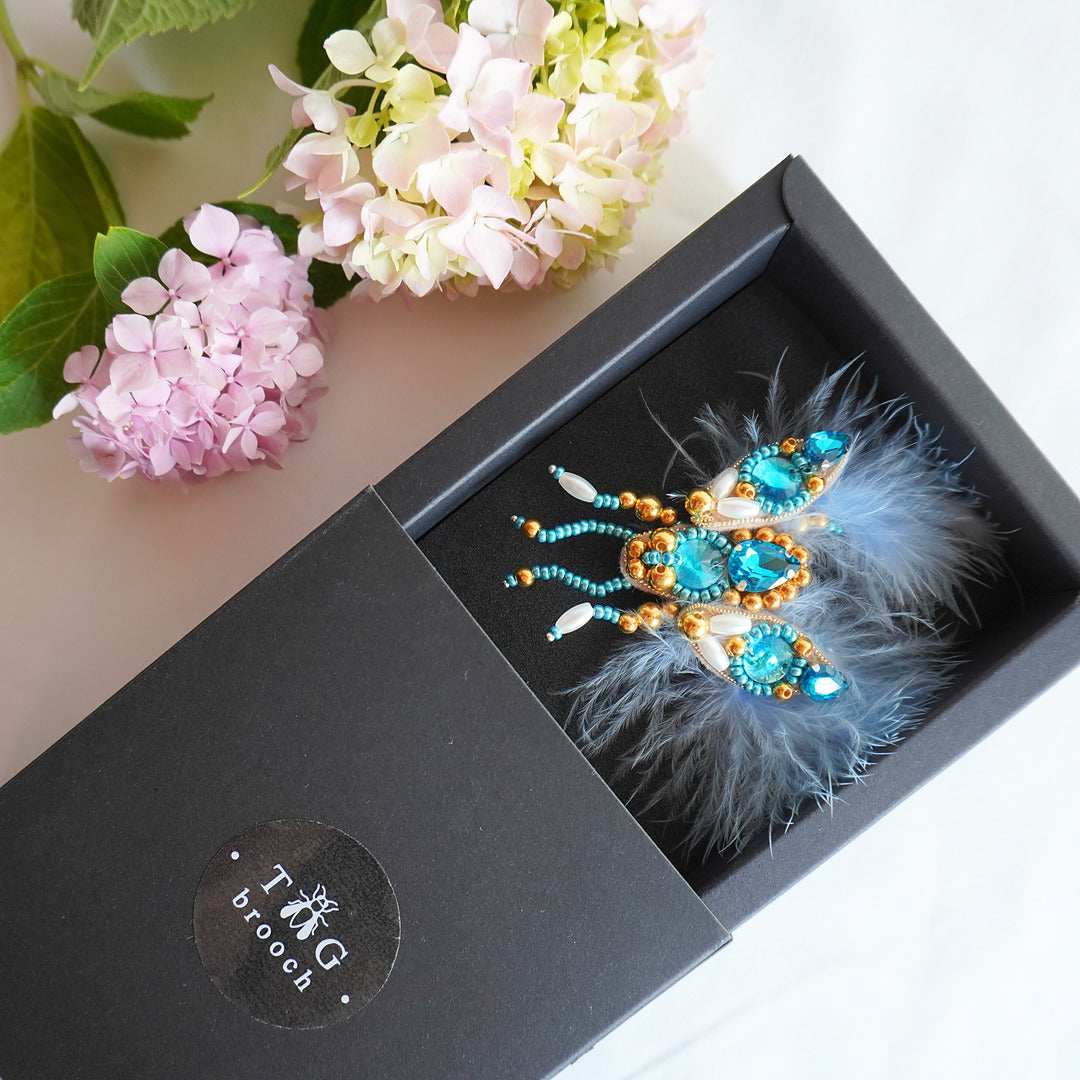 Handmade small size beaded fly brooch with azure blue gemstones, beads and feathers in a TGbrooch box