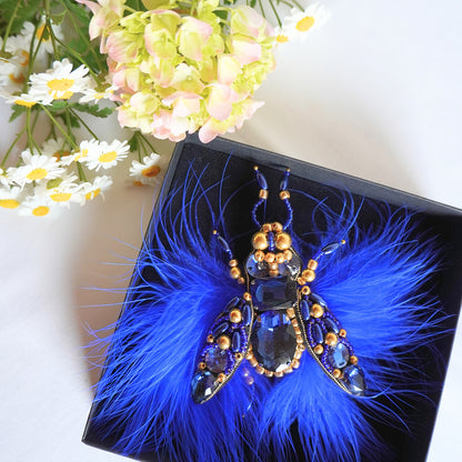 Embroidered TGbrooch with electric blue and gold beads and blue feathers