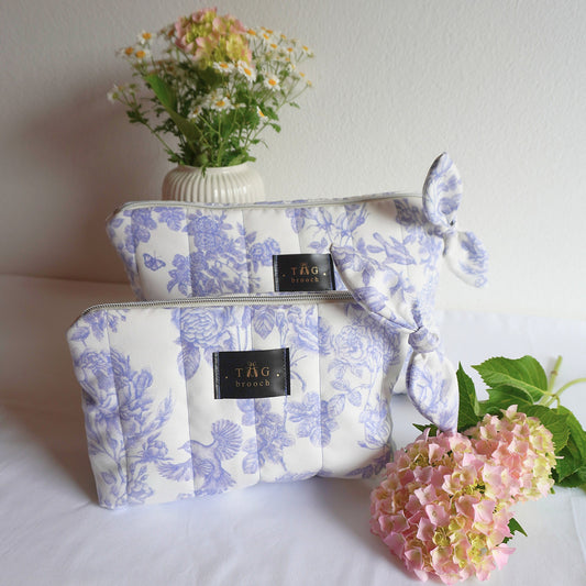 Two floral-patterned pouches with a brand label and botanical pattern in white and blue combination - TGbrooch